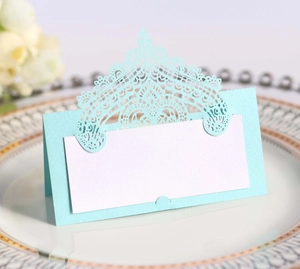 Macro detail of laser-cut lace place card in light blue on elegant white china plate