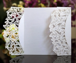 Détail de motifs papillons découpés au laser sur une carte d'invitation blanc perle
