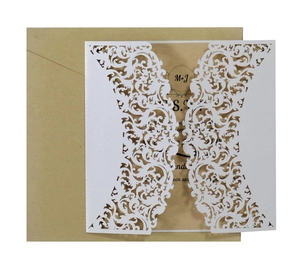 Detail of laser-cut white floral lace wedding invitation with a brown kraft envelope