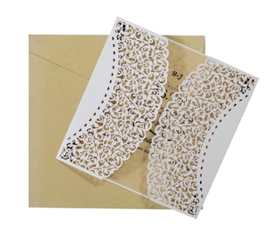 Detail of laser-cut white wedding invitation with floral vine pattern and kraft insert