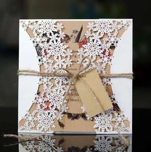 Close-up of laser-cut snowflake invitation with vintage floral kraft card and hemp rope