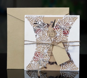 Detail of laser-cut spider web wedding invitation with kraft paper cards and twine