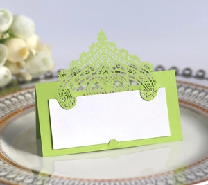 Close-up of laser-cut green lace wedding place card on an elegant white china plate