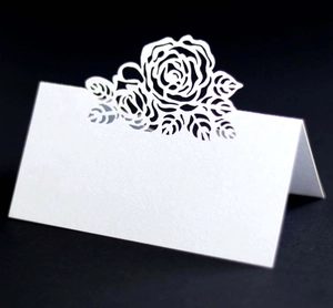 Macro detail of laser-cut white rose floral design on high-quality wedding place card