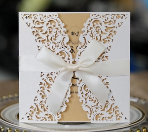 Detail of laser-cut floral wedding invitation with brown inner card and white silk ribbon
