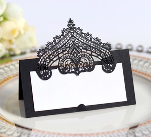 Macro detail of laser-cut crown lace pattern on black wedding place cards on a plate