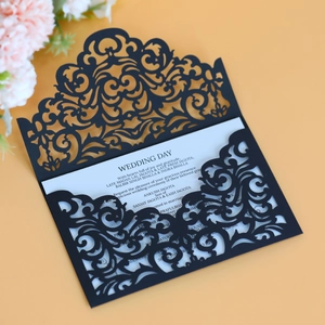 Close-up of laser-cut wedding invitation with elegant black lace pattern and white insert