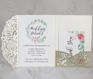 Detail view of laser-cut rose patterns on ivory and gold glitter wedding invitation set