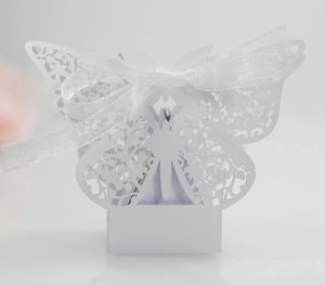 Macro view of white laser-cut butterfly wedding candy box with elegant silk ribbon bow