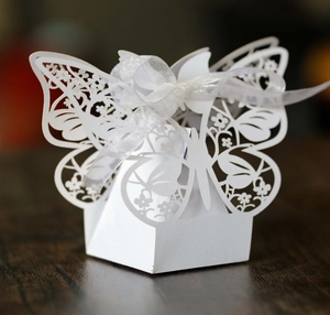Detailed laser-cut butterfly gift box with white ribbon on a dark wooden background