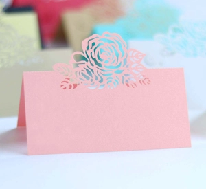 Detail of pink laser-cut rose place card with elegant floral hollow design for tables