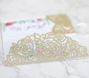 Macro detail of laser-cut gold glitter rose invitation card with floral insert