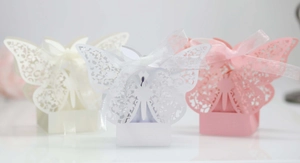 Macro detail of laser-cut butterfly wedding favor boxes with elegant silk ribbons