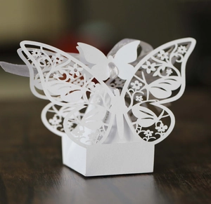 Macro detail of laser-cut butterfly wedding favor box with white ribbon on wood