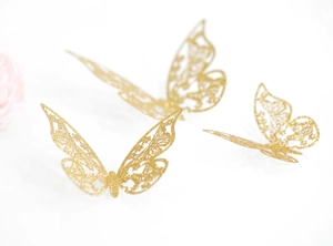 Detalle de pegatinas de pared de mariposa 3D doradas con brillo y diseño de encaje