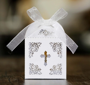 Detail of white laser-cut gift box featuring hollow cross and floral pattern with ribbon