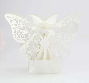 Detail of white laser-cut butterfly favor box with elegant silk ribbon and floral patterns