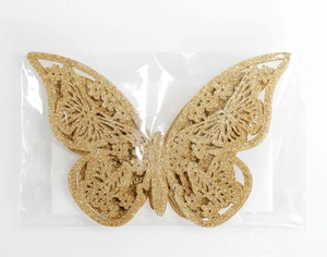 Detalle de mariposas 3D doradas con purpurina huecas en un embalaje transparente