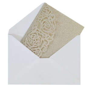 Detail of laser-cut gold glitter wedding invitation featuring intricate rose patterns