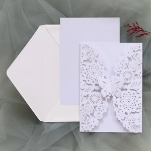 Dettaglio dell'invito di nozze tagliato al laser con motivi di farfalle e fiori intricati