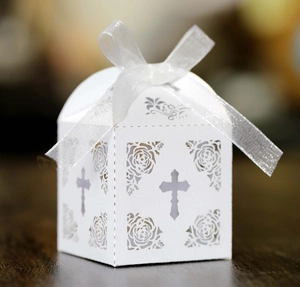 Detail of white laser-cut candy box with hollow cross and floral pattern and ribbon