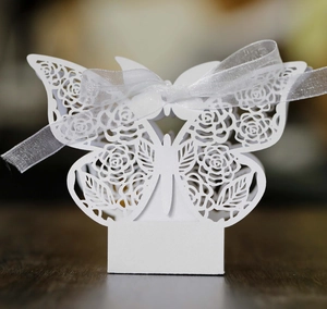 Detail of laser-cut white butterfly candy box with rose pattern and silver ribbon
