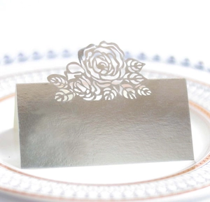 Close-up of laser-cut silver rose place card displayed on an elegant dinner plate