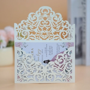 Macro shot of laser-cut wedding invitation with cream floral inner card and intricate patterns