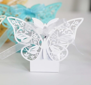Close-up of laser-cut white butterfly candy box with delicate floral patterns and silk ribbon