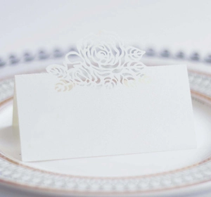 Close-up of laser-cut rose floral place card on elegant dinner plate for weddings