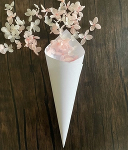 White wedding confetti cone with pink and white dried hydrangea flowers on wood background