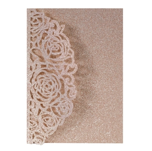 Detail of rose gold glitter laser-cut invitation sleeve with intricate rose floral patterns