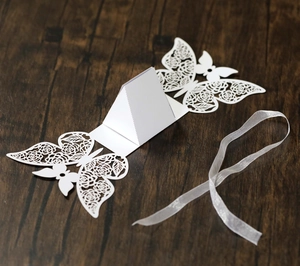 Detailed laser-cut white butterfly candy box with rose patterns and ribbon on wood
