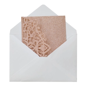 Detail of rose gold glitter wedding invitation with laser-cut lace and white envelope