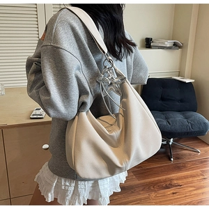 Detail of cream crescent tote featuring herringbone texture and silver star charm