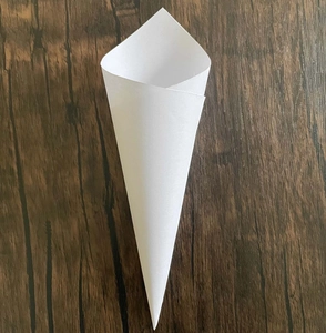 Macro view of white paper petal cones for wedding confetti on dark wood background