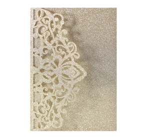 Macro detail of laser-cut floral pattern on champagne gold glitter wedding invitation