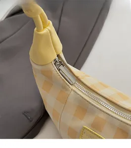 Detail of silver zipper closure on yellow and white checkered canvas shoulder bag