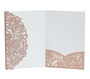 Macro view of laser-cut rose gold glitter wedding invitation with floral hollow pattern