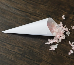 Detailed view of a white paper confetti cone filled with pink and white flower petals