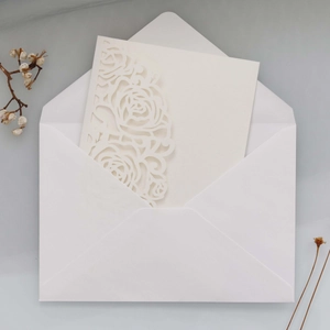 Détail d'invitation de mariage découpée au laser avec roses et enveloppe blanche