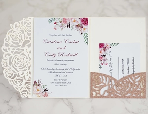 Detail of laser-cut white rose wedding invitation with rose gold glitter insert