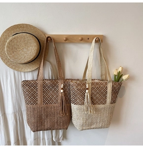Detail of woven straw tote bags with wooden bead tassels in a vacation beach setting