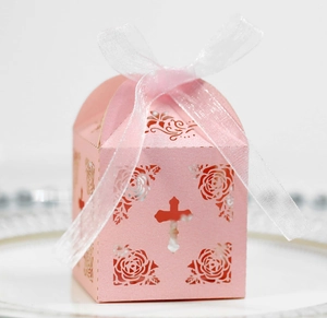 Detail of pink laser-cut gift box with hollow cross and floral pattern for weddings
