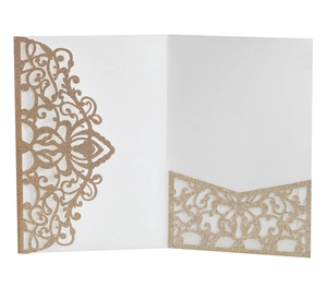 Macro detail of intricate laser-cut golden glitter vine patterns on wedding invitation cards