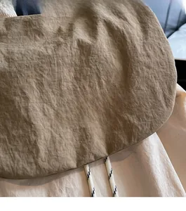 Close-up of khaki nylon texture with brand logo and braided drawstring detail