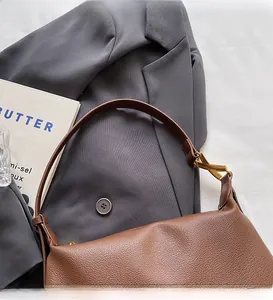 Close-up of brown textured leather shoulder bag with elegant gold metal buckle detail