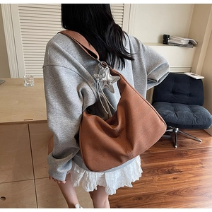Brown hobo shoulder bag with herringbone texture and star pendant in a lifestyle scene