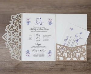 Detail of laser-cut white lace wedding invitation with gold glitter pocket and purple floral card