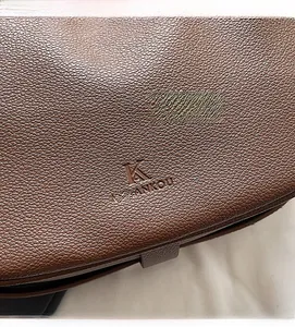 Macro detail of brown litchi pattern leather bag showing embossed Mulankou logo